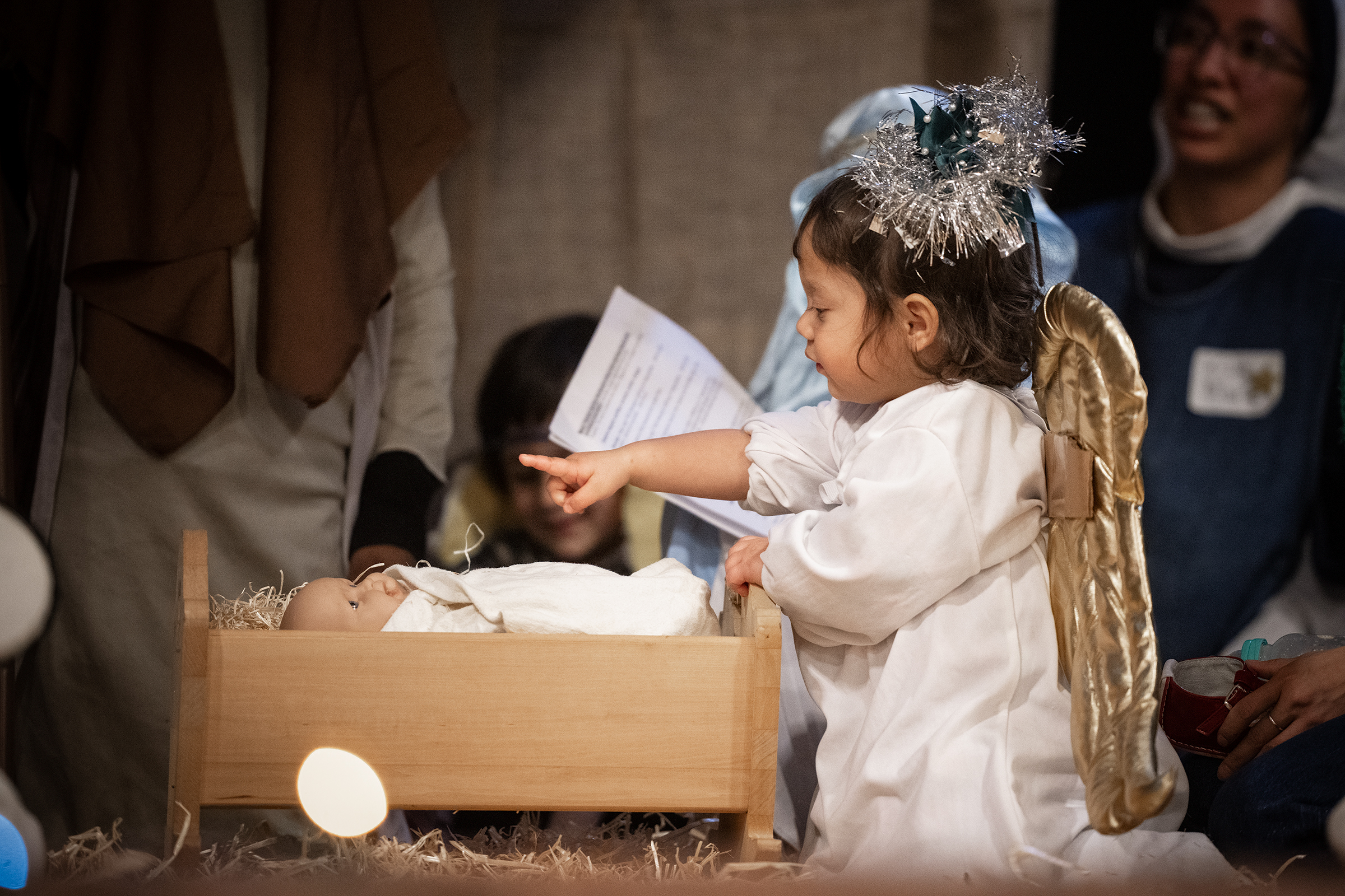 A tiny angel reaches toward the Baby Jesus in the manger
