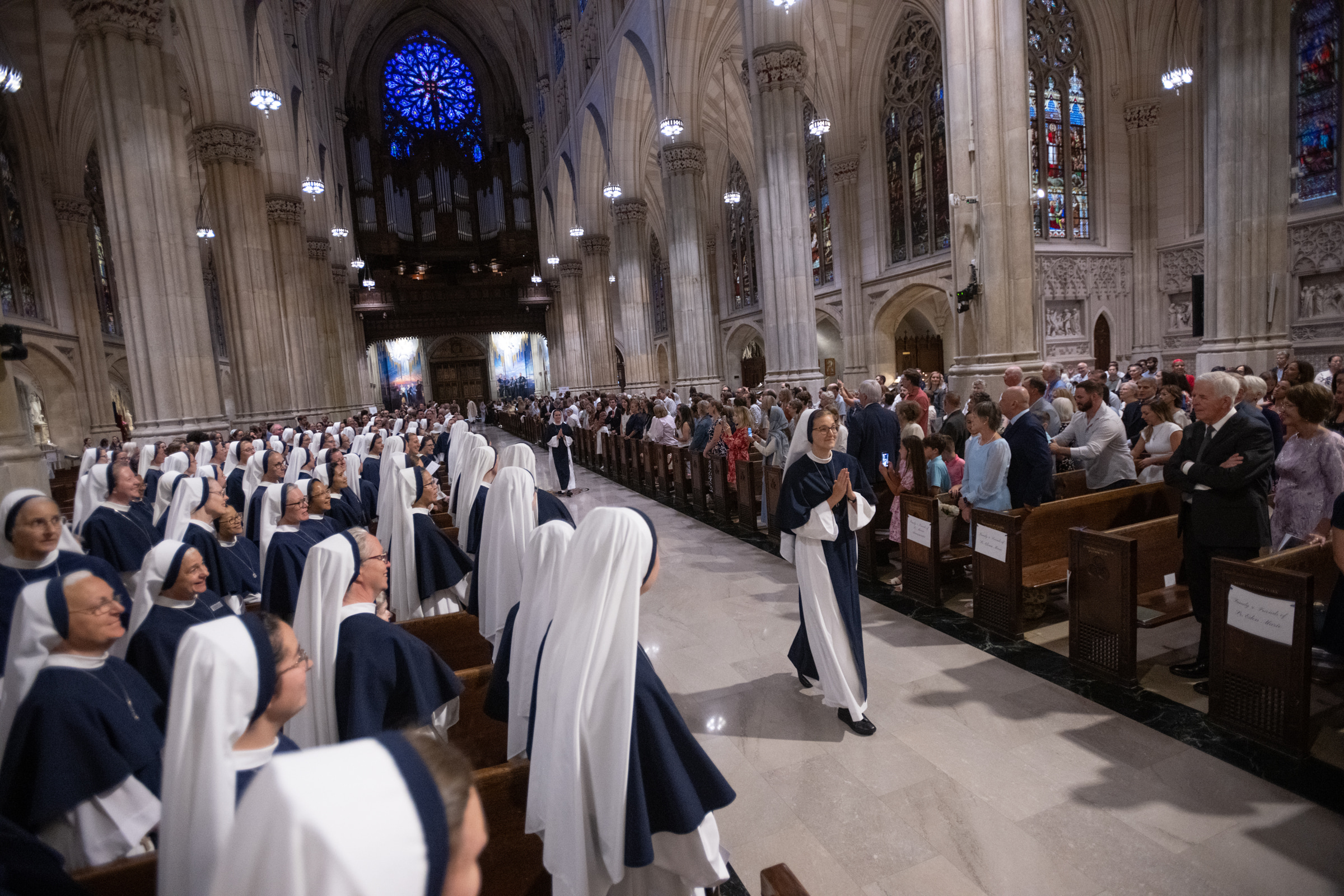 Sister Elena Marie, S.V., walks down the cathedral aisle with her hands folded in prayer.