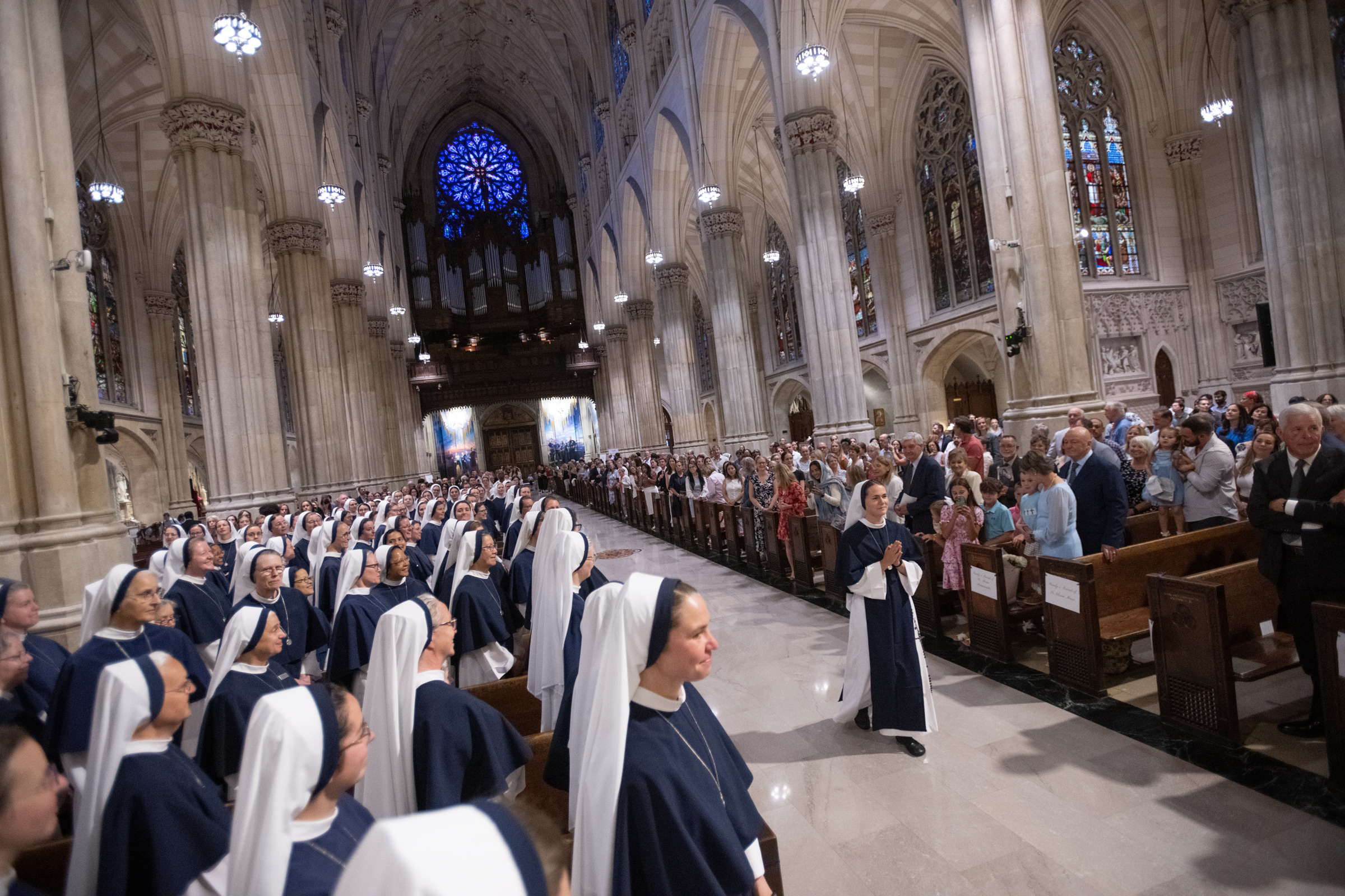 Sister Maria Annunciata, S.V., walks down the cathedral aisle with her hands folded in prayer.