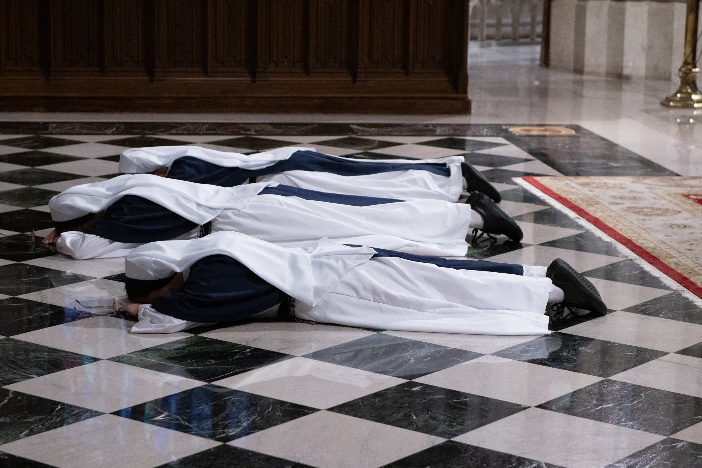 A closer view of the three Sisters lying prostrate on the cathedral floor during the Litany of the Saints.