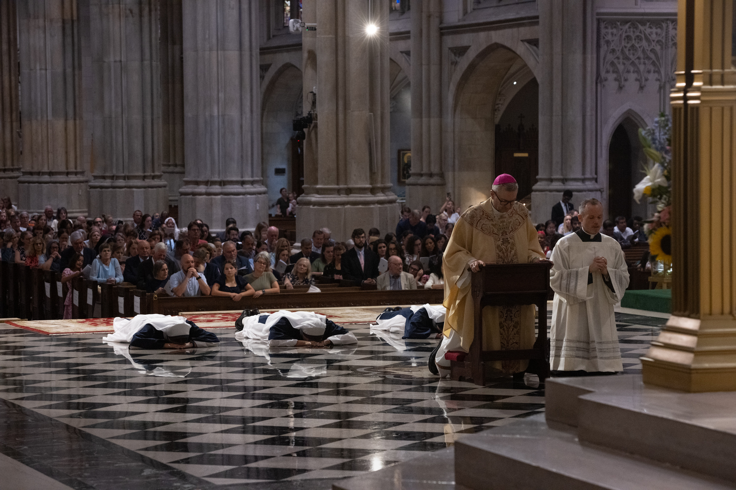 Archbishop Hicks kneels in prayer as the three Sisters lie prostrate during the Litany of the Saints