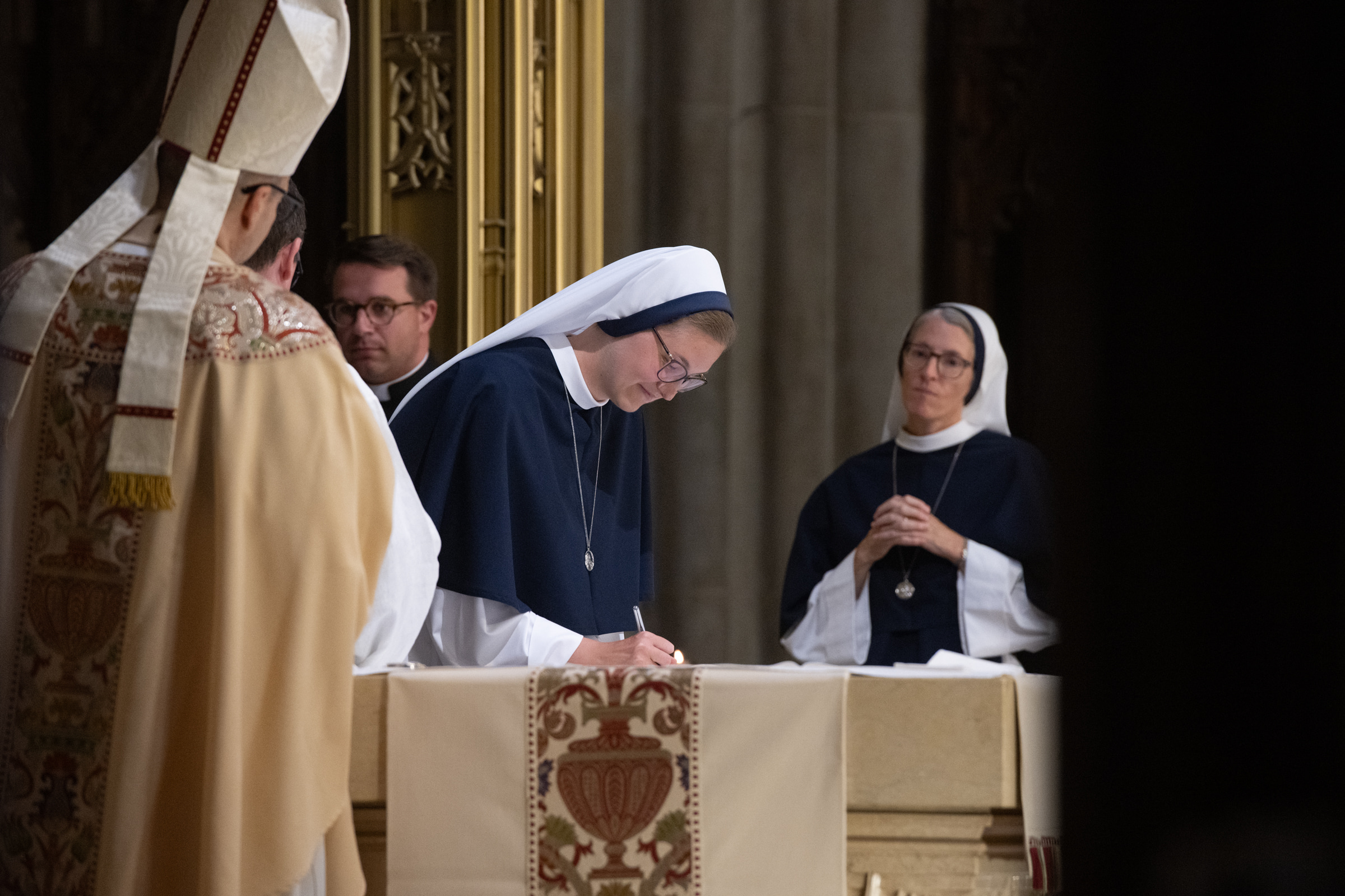 Sister Elena Marie, S.V., signs the record of her profession at the altar.