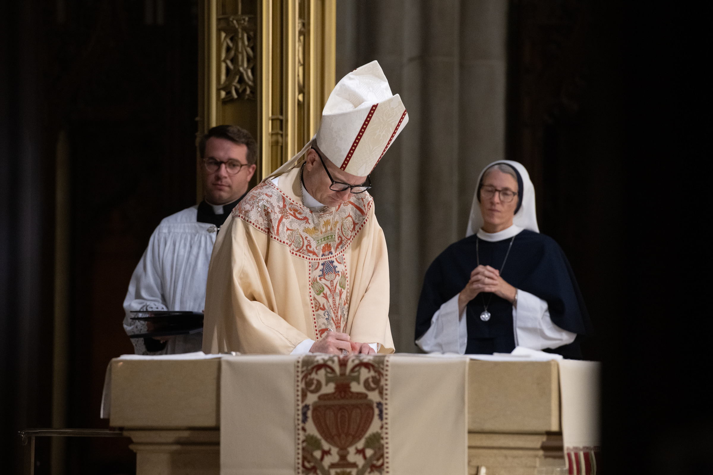 Archbishop Hicks signs the profession record at the altar.
