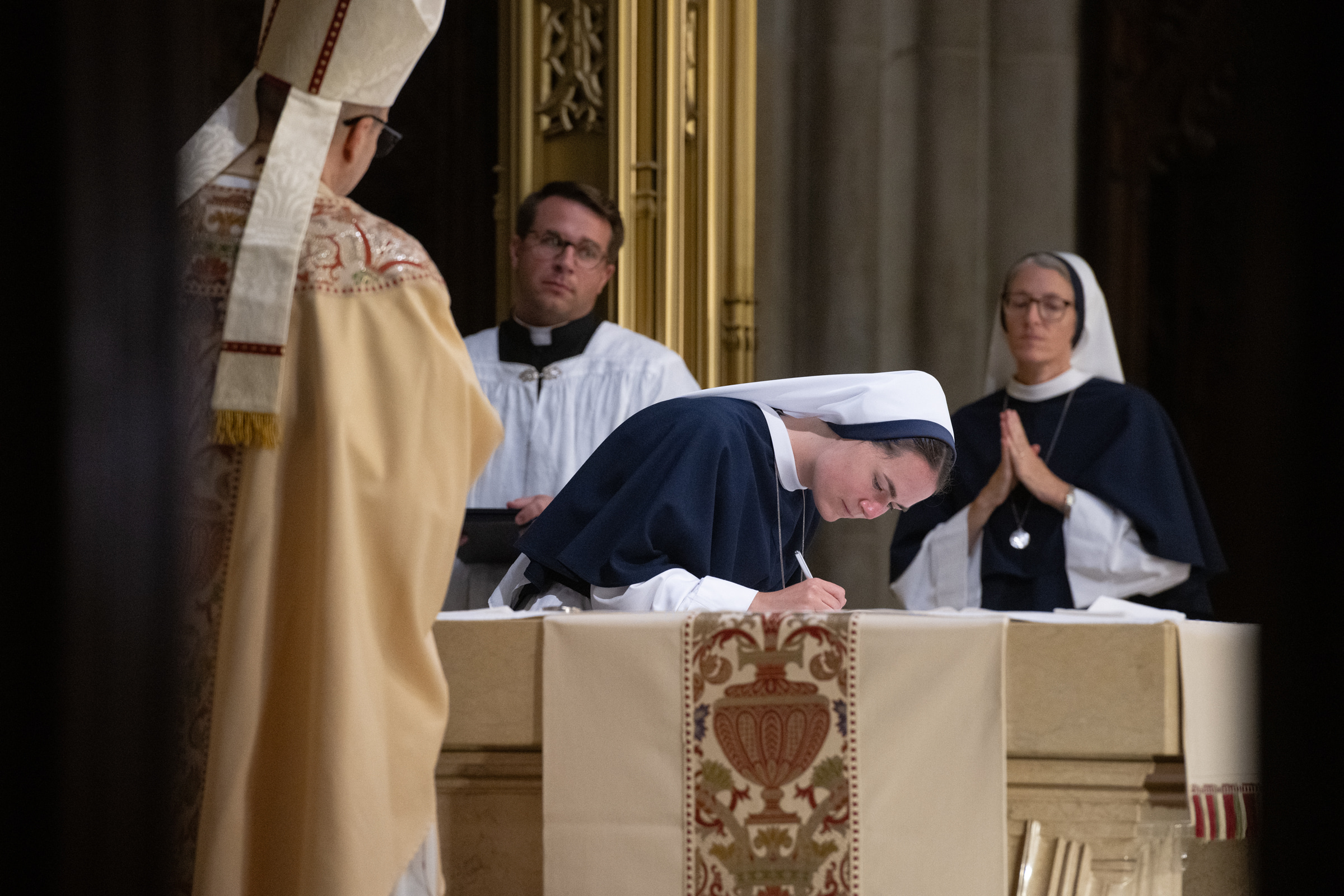 Sister Maria Annunciata, S.V., signs the record of her profession at the altar.