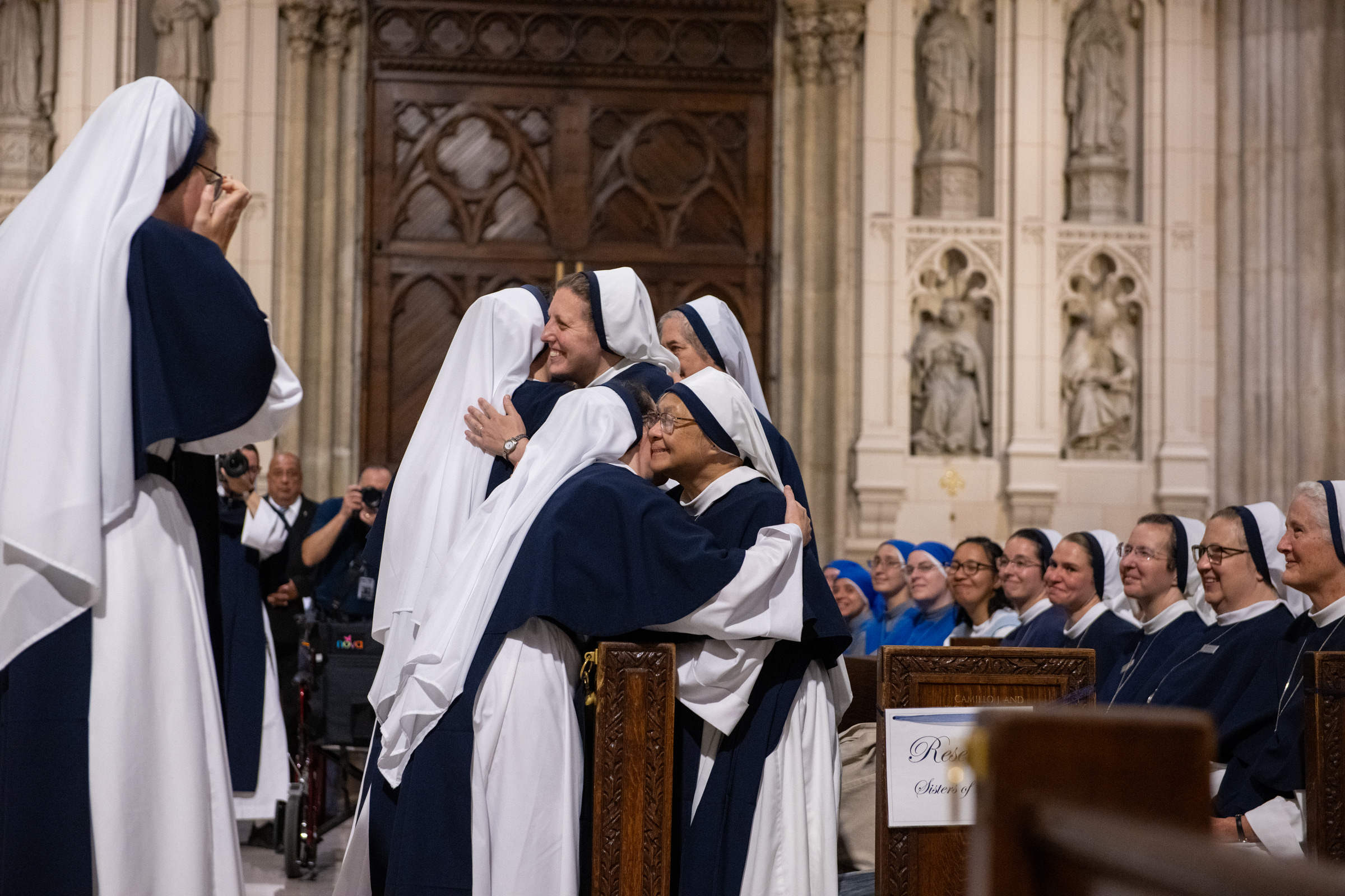 Sisters embrace in celebration while the community watches from the pews.