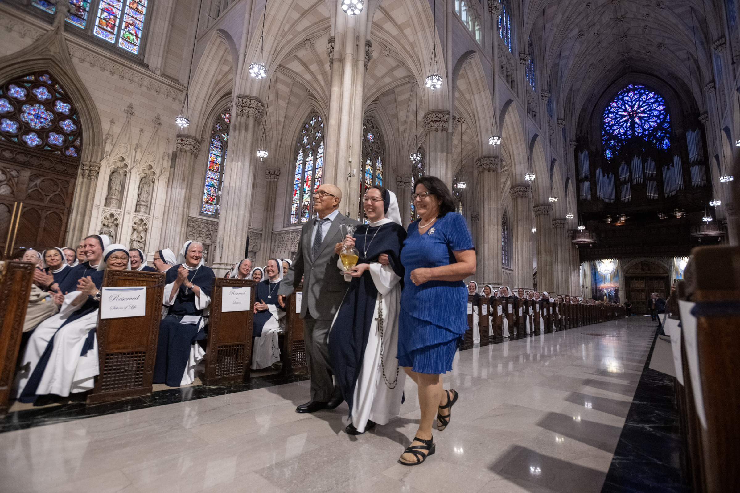 Sister Eden Marie, S.V., walks between two guests carrying a glass cruet in the offertory procession.