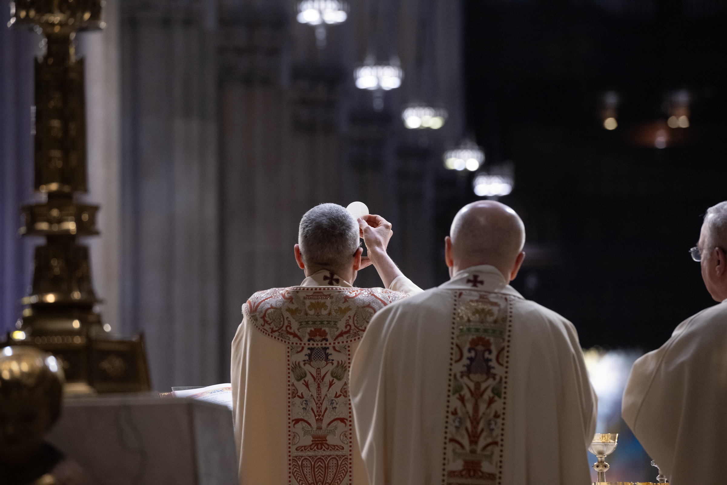 The Host is elevated during Mass beneath the dark vaults of St. Patrick’s Cathedral